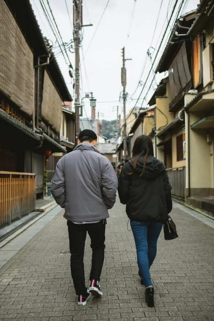 A young couple strolls through the traditional streets of Gion, Kyoto. Experience the serene ambiance and historic charm.